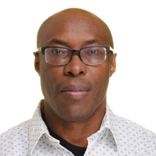Headshot of poet Umezurike Peter Uchechukwu, a Black man with a shaved head. He is wearing square-shaped glasses and a white collared shirt.